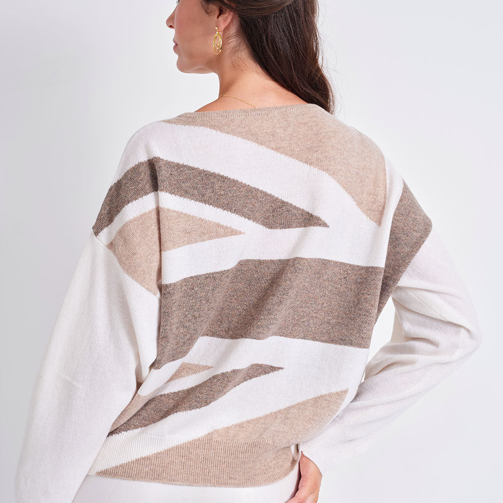 A woman shown from the back wearing a knit sweater with a geometric abstract pattern in beige, taupe, and white.