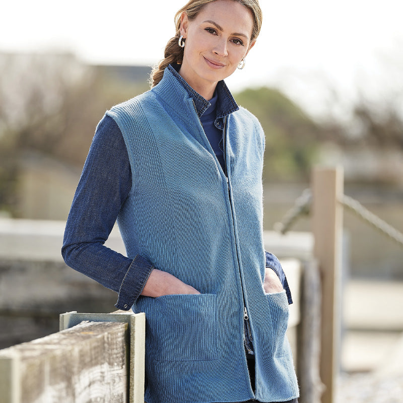 Woman wearing a cashmere blue zip-up vest outdoors with a blurred background