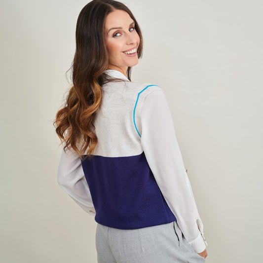 Woman wearing a cashmere  two-tone shirt with a white front and blue back, standing against a plain background.