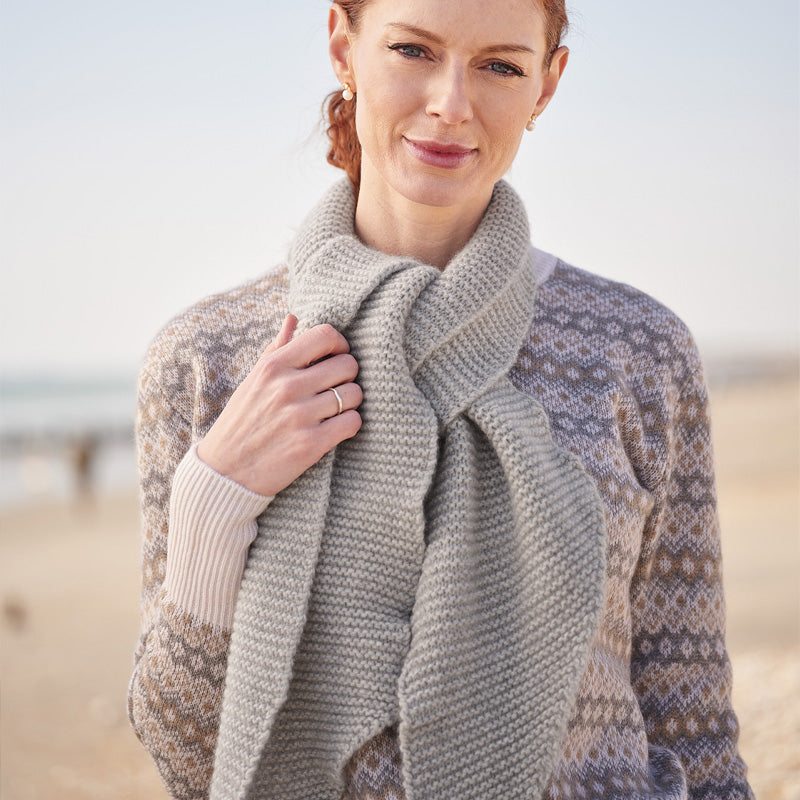 Woman wearing a grey cashmere scarf on a beach