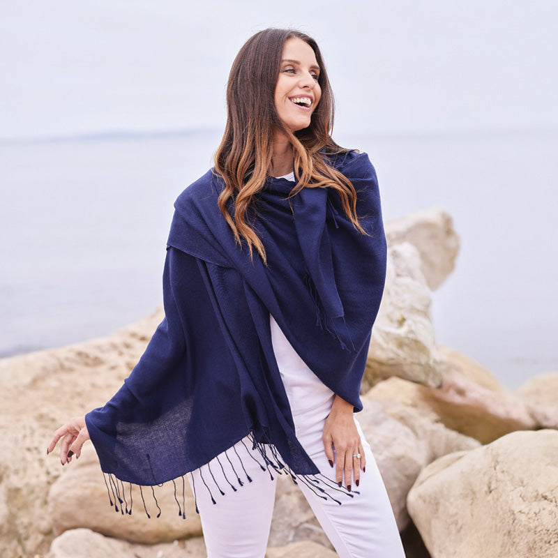Woman wearing a blue wrap with fringe on a rocky beach