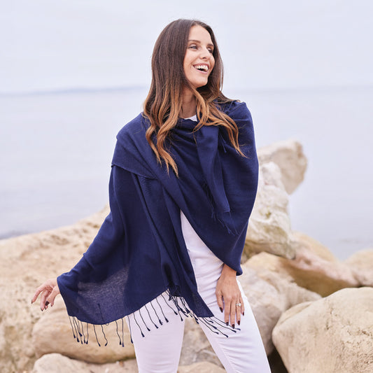 Woman wearing a blue wrap with fringe on a rocky beach