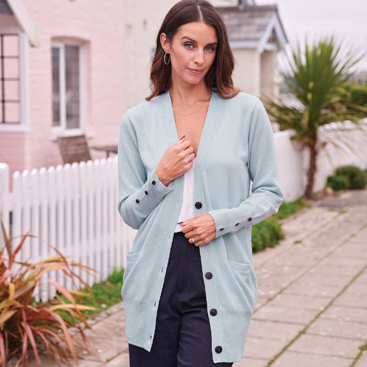 Woman wearing a cashmere light blue cardigan with black buttons outdoors.