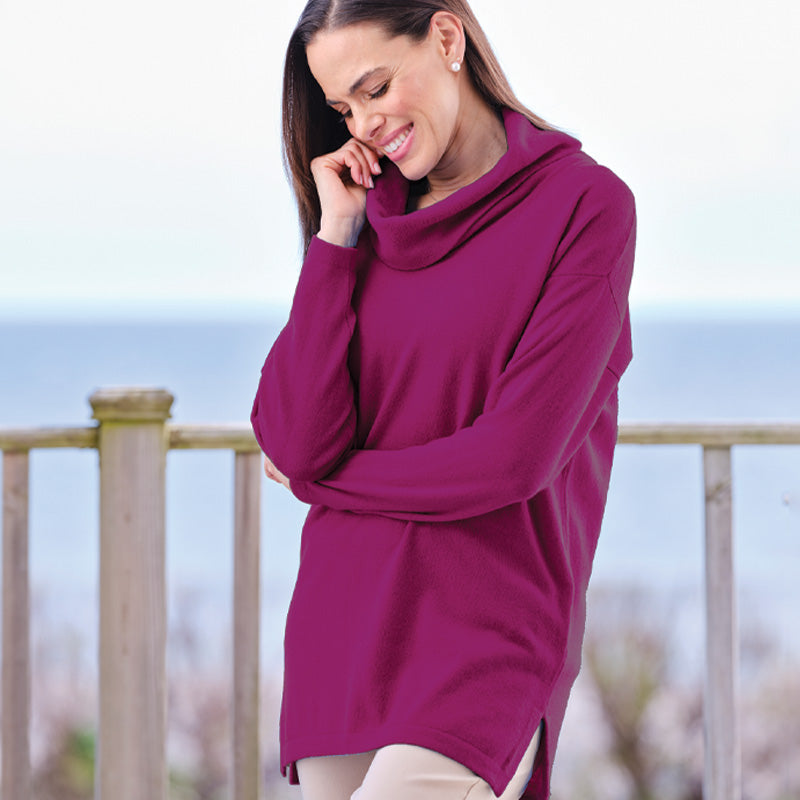 Woman wearing a magenta Cashmere sweater by a wooden railing with a blurred background