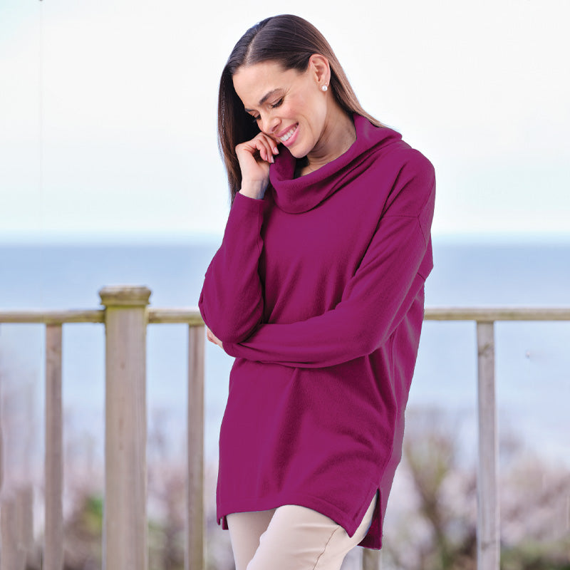 Woman in a purple Cashmere sweater talking on a phone outdoors