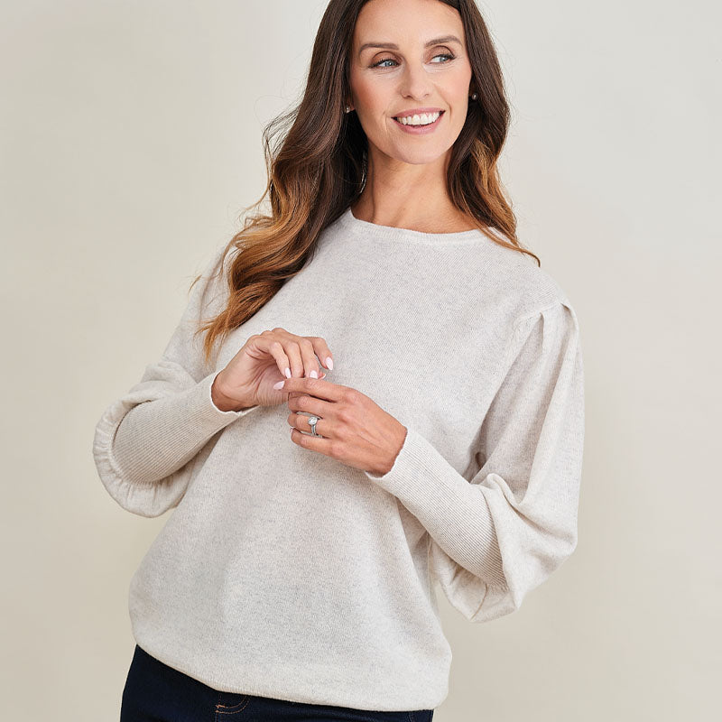 Woman wearing a cashmere beige sweater against a plain background