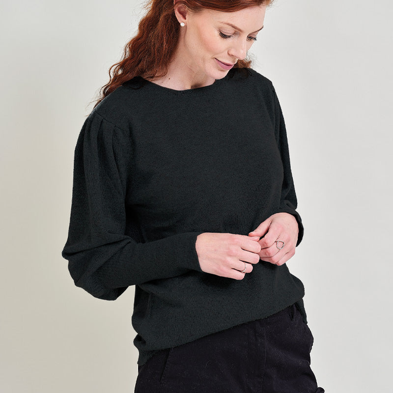 Woman wearing a cashmere black sweater against a plain background