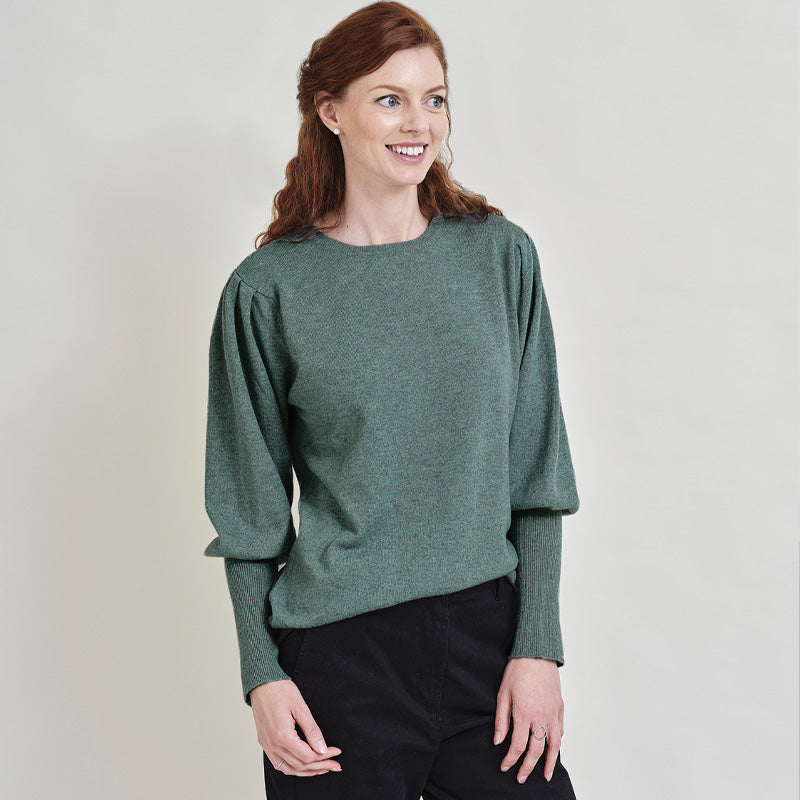 Woman wearing a green cashmere sweater against a plain background