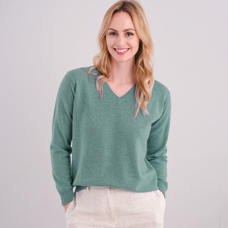 Woman wearing a green sweater on a plain background