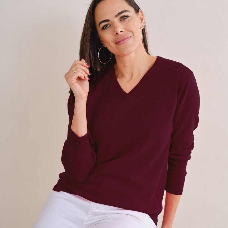 Woman wearing a burgundy sweater against a plain background