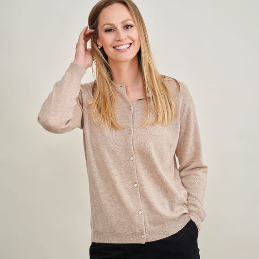 Woman wearing a cashmere beige cardigan against a plain background
