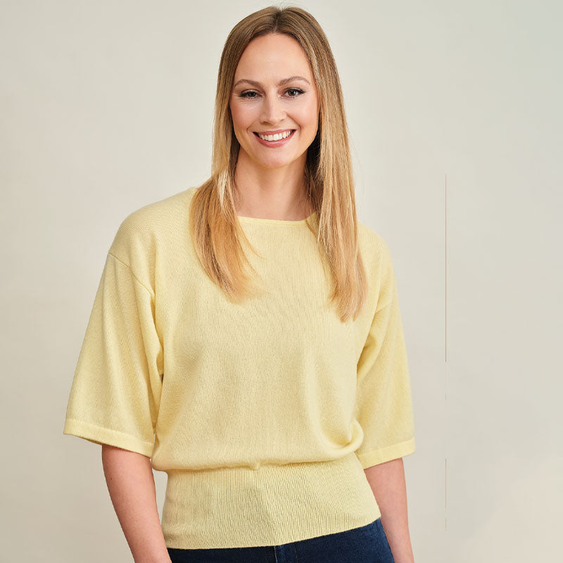 Woman wearing a cashmere light yellow sweater against a plain background