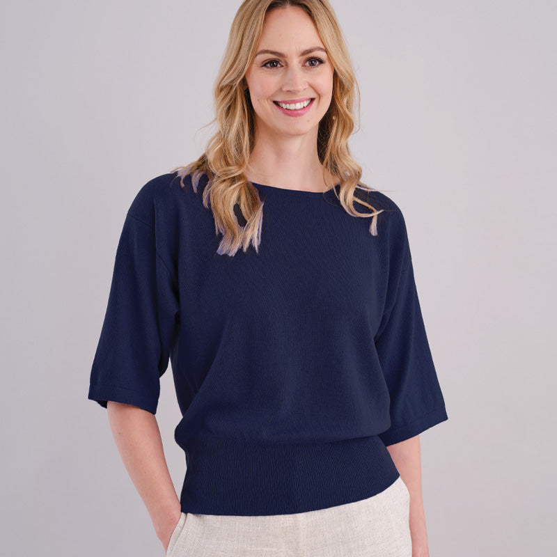 Woman wearing a cashmere dark navy blue top against a plain background