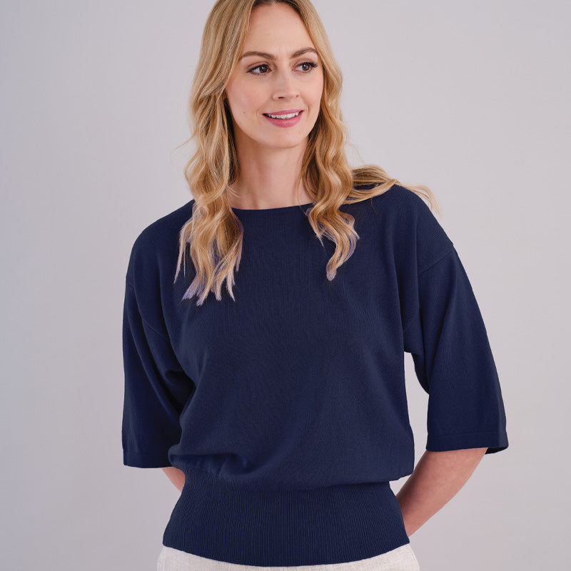 Woman wearing a dark navy blue cashmere sweater against a plain background