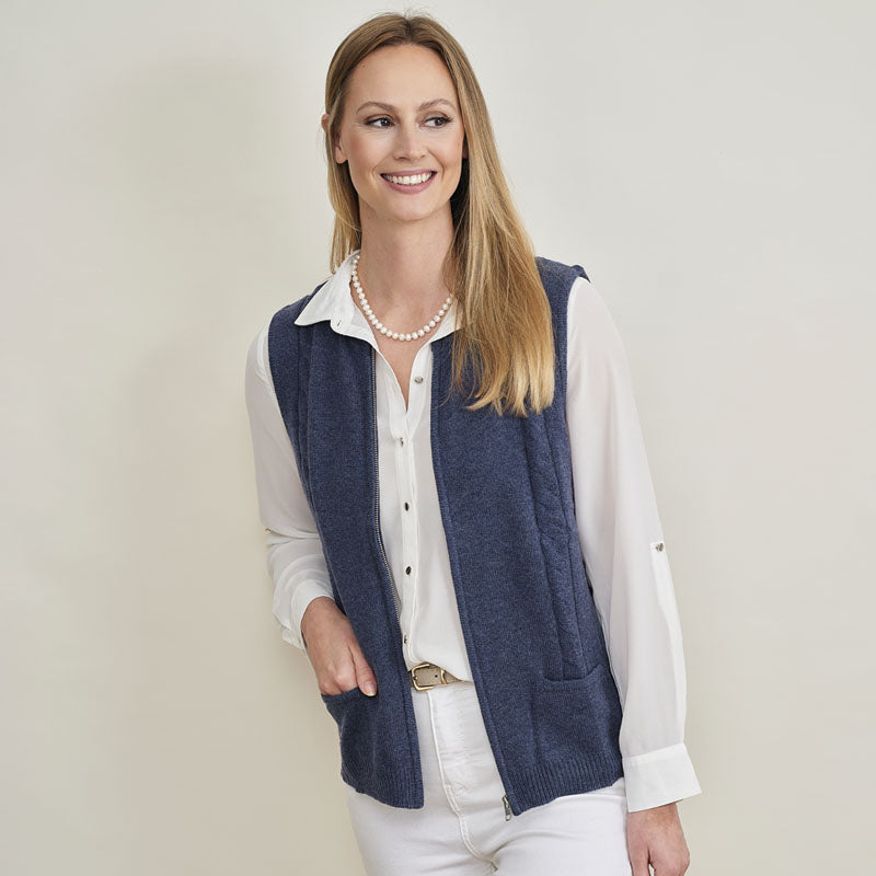 Woman wearing a cashmere navy vest over a white shirt on a plain background