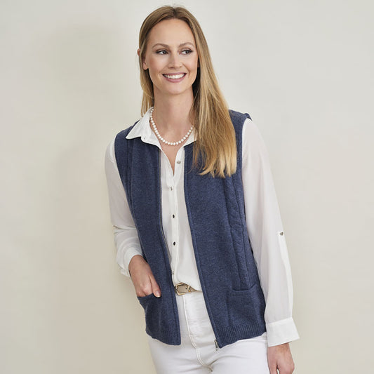 Woman wearing a cashmere navy vest over a white shirt on a plain background