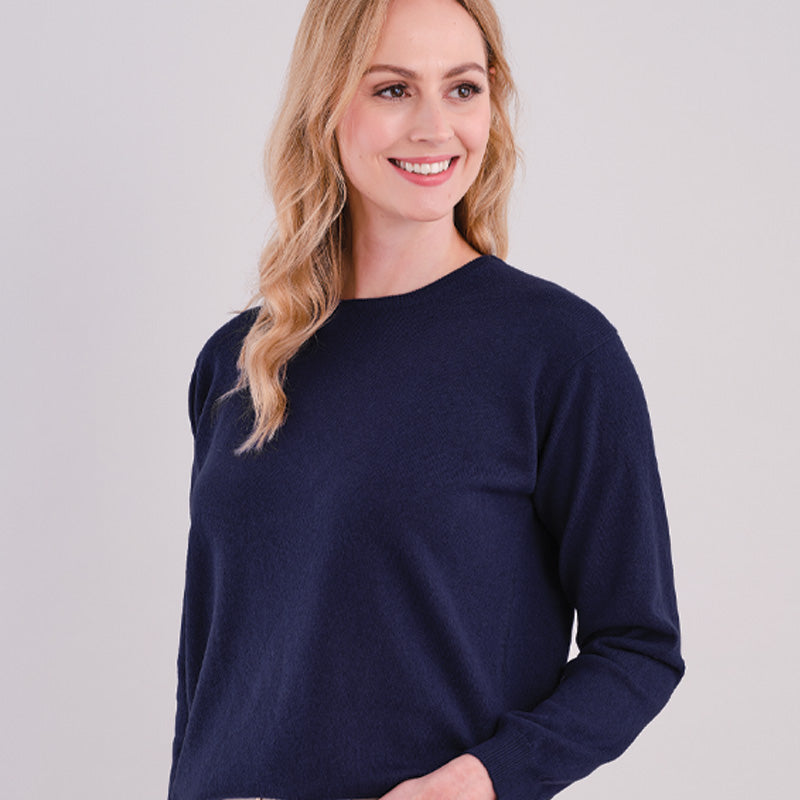 Woman wearing a  cashmere navy blue sweater against a light gray background