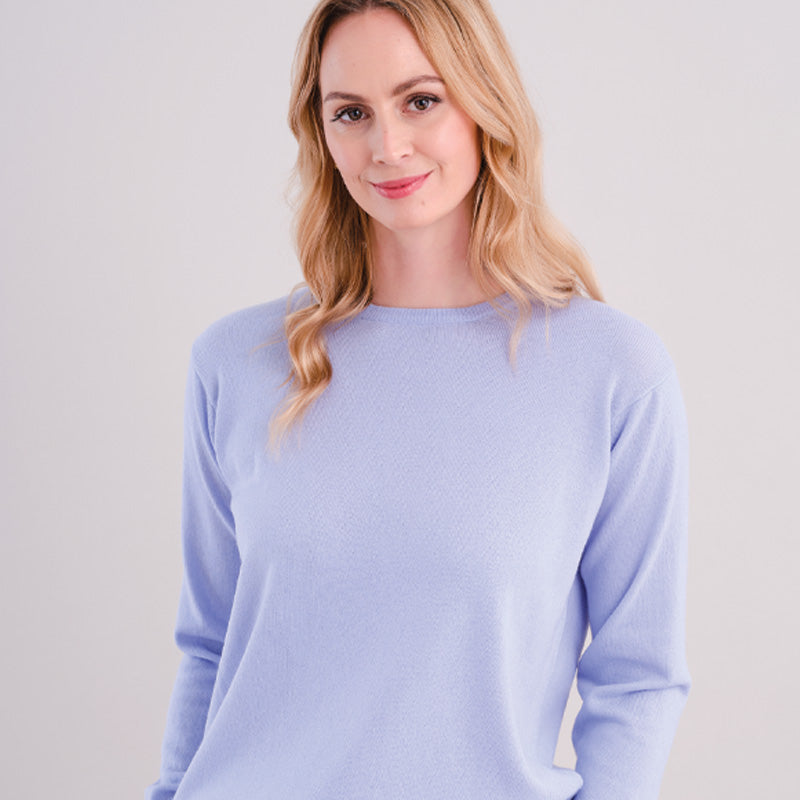 Woman wearing a cashmere light blue sweater against a plain background