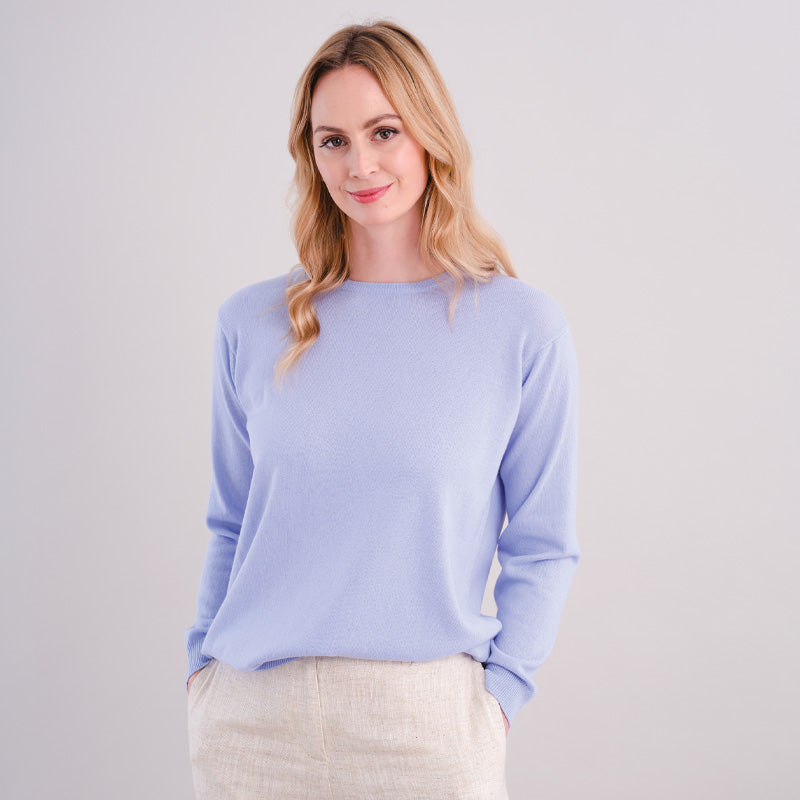 Woman wearing acashmere light blue sweater against a plain background