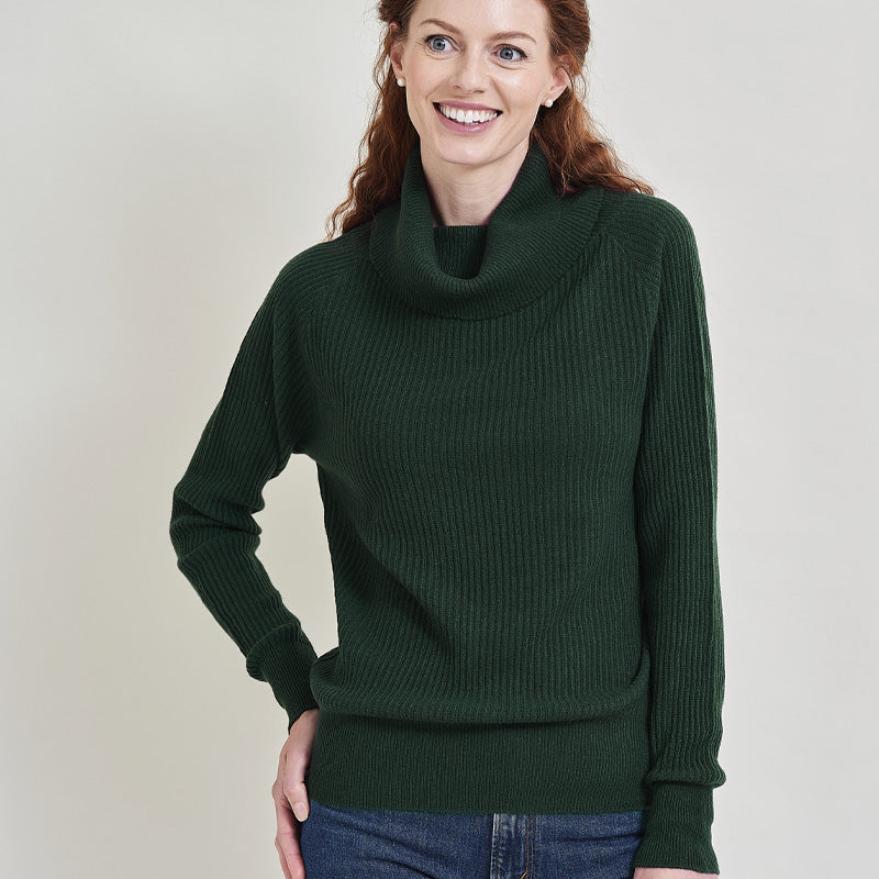 Woman wearing a cashmere dark green sweater against a plain background