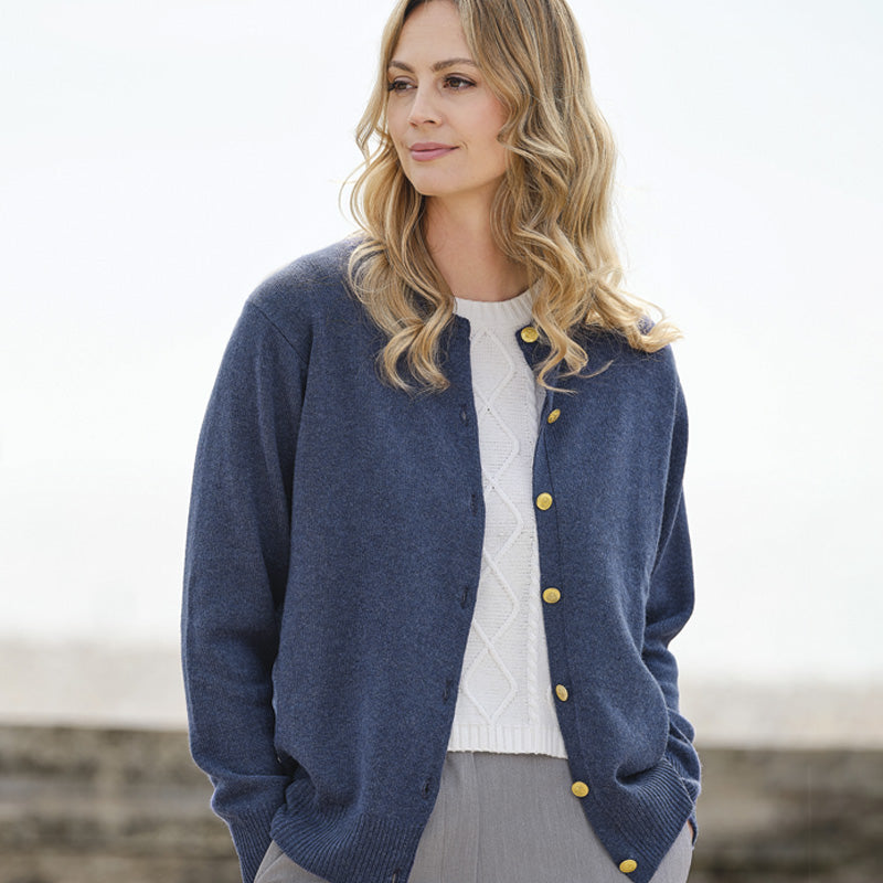 Woman wearing a blue cashmere cardigan with gold buttons outdoors