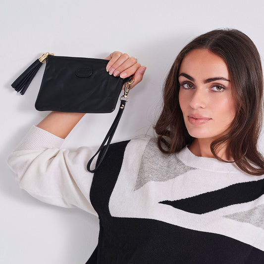 Woman holding a black handbag with a tassel on a light background