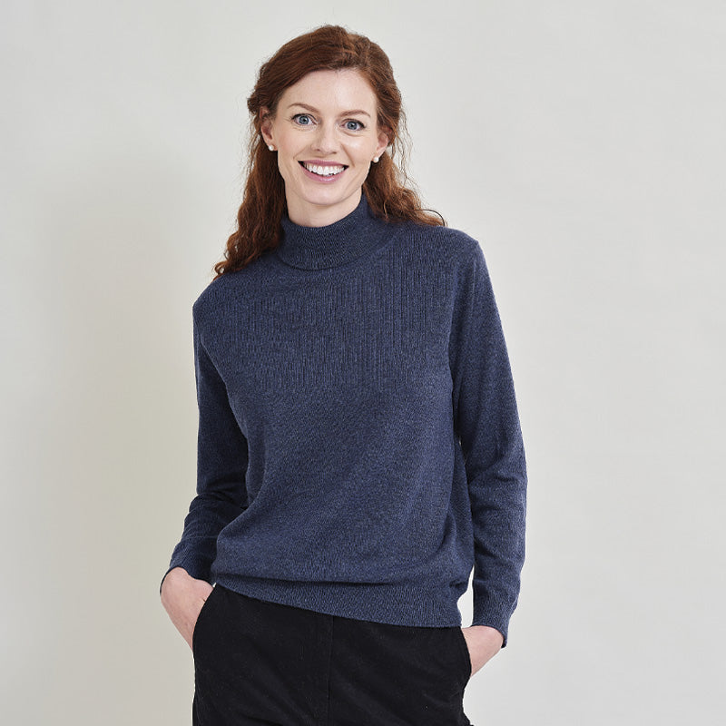 Woman wearing a denim blue cashmere sweater against a plain background
