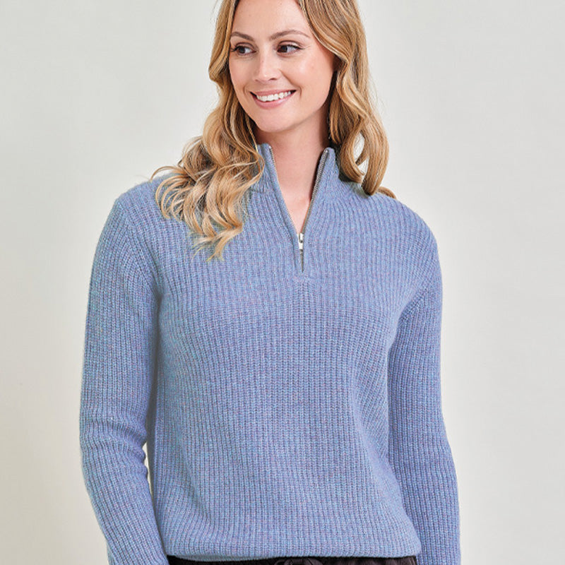 Woman wearing a cashmere blue ribbed sweater against a plain background