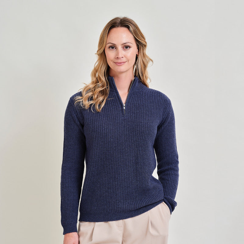 Woman wearing a cashmere dark denim blue sweater with a zipper on a light gray background