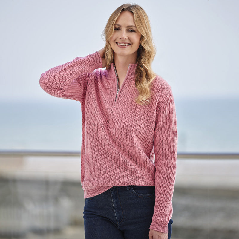 Woman wearing a cashmere pink ribbed sweater with a blurred background